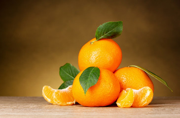 Ripe orange tangerines with segments on brown background