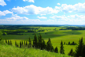 Valley with green meadows forests and villages. View from top of a hill
