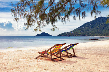 Two sun beach chairs on shore near sea