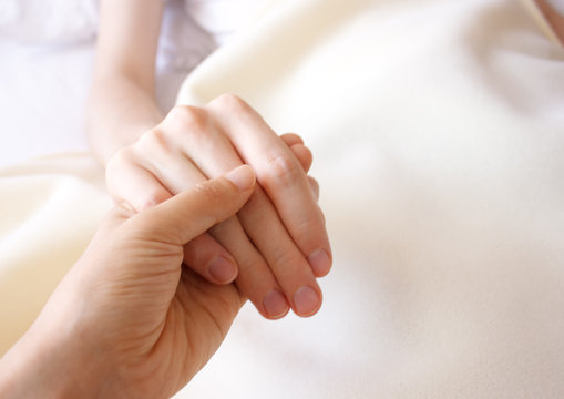 Holding the hand of a sick loved one in hospital bed