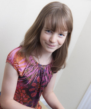Smiling preteen girl sitting at the piano