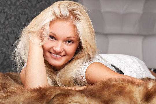 Beautiful smiling blond girl on a fur