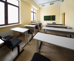 Empty beige classroom with wooden school desks