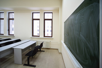 Big green school board inside empty beige classroom