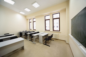 Empty beige classroom with wooden school desks