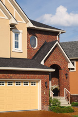 Entrance in new two-storied brown brick cottage with garage