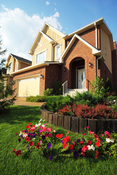 Garden with flowers in front of two-storied brick house