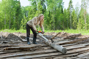 woman in wood saws a tree a chain saw