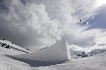 snowboarder taking big air jump with cloudy sky