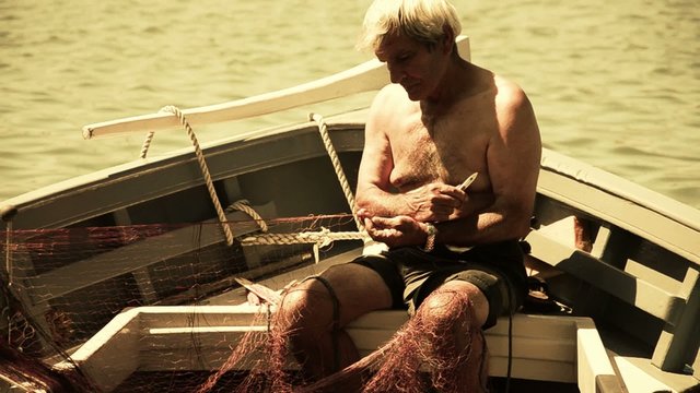 sardegna, pescatore aggiusta una rete