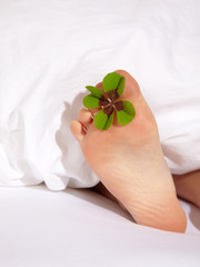 Happy feet of a child under a white blanket with shamrock