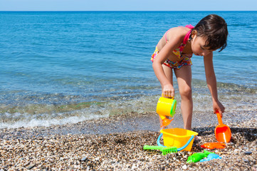 Little girl playing with toys on the beach