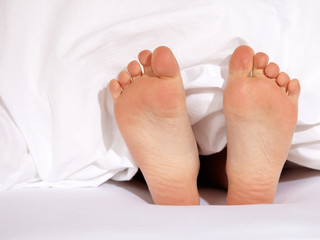 .Happy  bare feet of a child under a white blanket