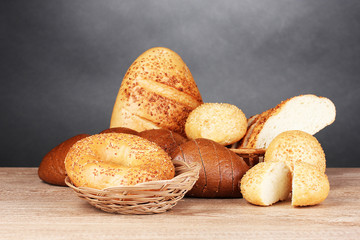 rye and white bread and buns on wooden table on gray background