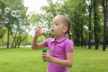 Little girl in the park blowing bubbles