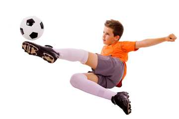 Fototapeta premium Young boy with soccer ball doing flying kick, isolated on white