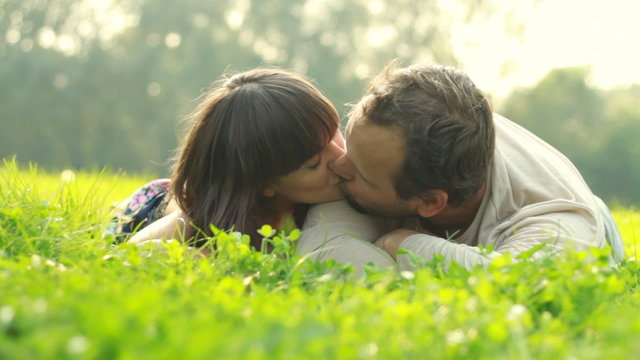 Happy couple lying on grass and kissing