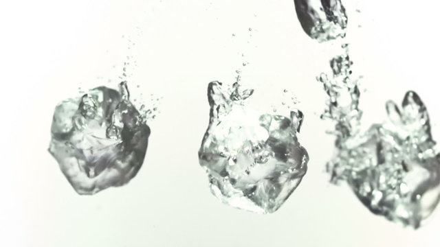 Ice cubes splashing into water in slow-motion
