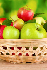 Fresh organic apples in basket on wooden table outside
