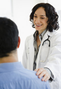Hispanic doctor talking to patient in doctor&rsquo;s office
