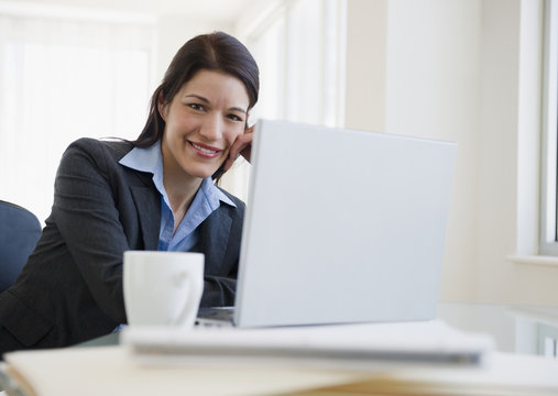 Mixed race businesswoman using laptop in office