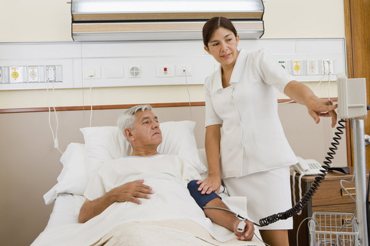 Nurse taking patient’s blood pressure in hospital room
