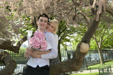 Caucasian couple with flowers kissing in park