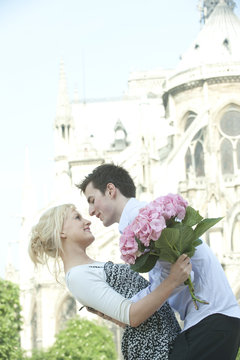 Caucasian couple about to kiss near historical landmark near Notre Dame