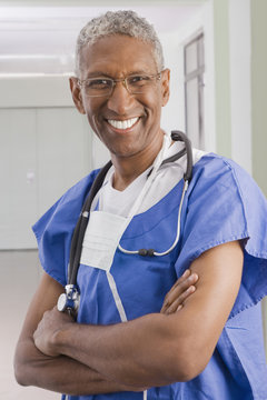 Smiling mixed race surgeon with arms crossed