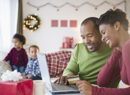 Black mother and father shopping online with credit card