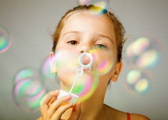 Portrait of funny lovely little girl blowing soap bubbles