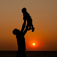 father and son at sunset sea