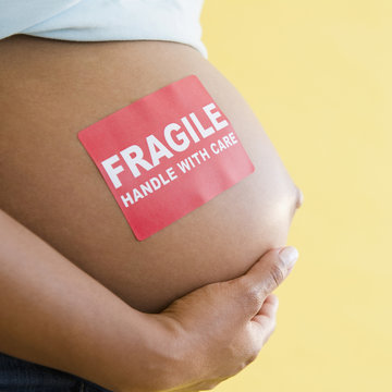 Naklejki Close up of 'Fragile' sticker on pregnant Black woman's stomach