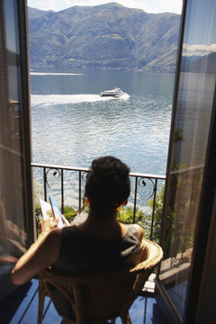 Italian woman sitting balcony looking at lake