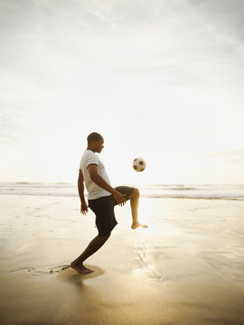 Man playing with soccer ball on beach