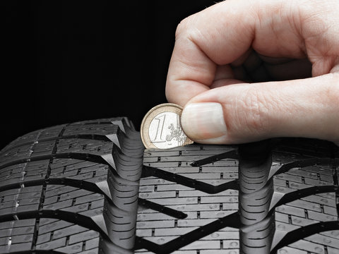 Checking the tread pattern of a winter tire with euro coin