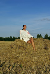 girl in traditional Russian costume sitting on a haystack