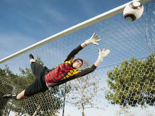 Mixed race goalkeeper in mid-air protecting goal