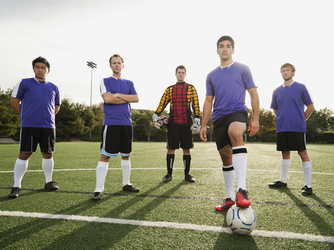 Men standing with ball on soccer field