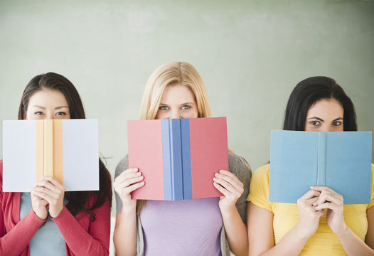 Women hiding behind books - Powered by Adobe