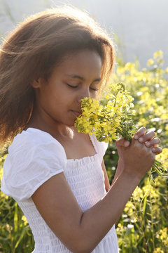 Mixed race girl smelling flowers