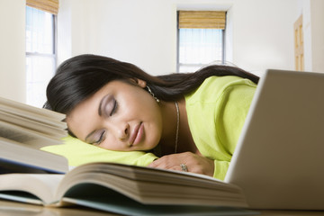 Hispanic woman sleeping on books