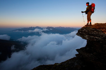 Fototapeta Man with backpack high above the misty mountain valley obraz