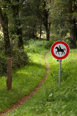 Verbotschild für Reiter vor einem idyllischen Wanderweg
