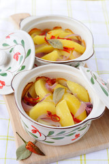 Two pots with baked potato with hot pepper and onion