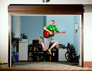 Young man with guitar have fun jumping and singing song.