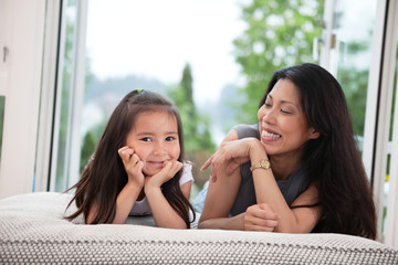 Mother and daughter on couch laughing