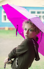 Young pretty girl stands under pink umbrella