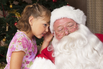 Fototapeta na wymiar Little girl whispers her Christmas list to Santa