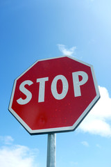 Stop sign against blue cloudy sky